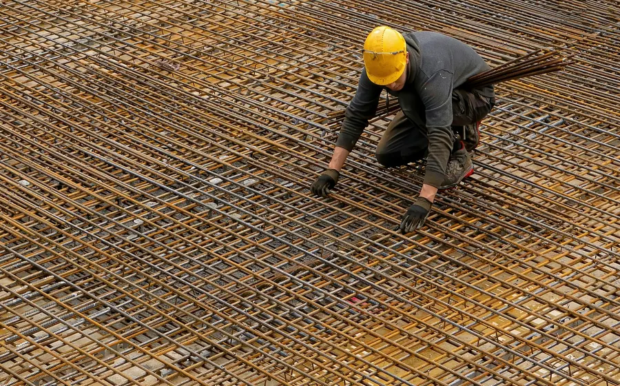 Trabajador con casco amarrando la malla de acero de un radier