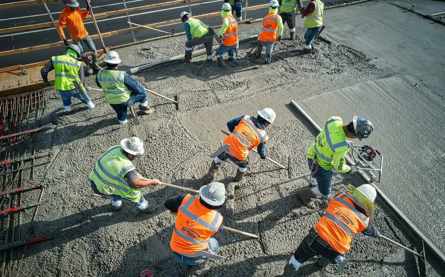 Cuadrilla nivelando hormigón fresco en una losa de gran superficie