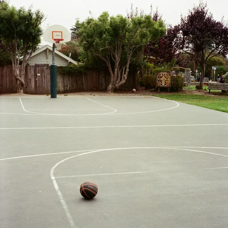 Cancha de hormigón con líneas pintadas y un balón de básquetbol