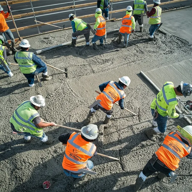 Cuadrilla nivelando hormigón fresco en una losa de gran superficie