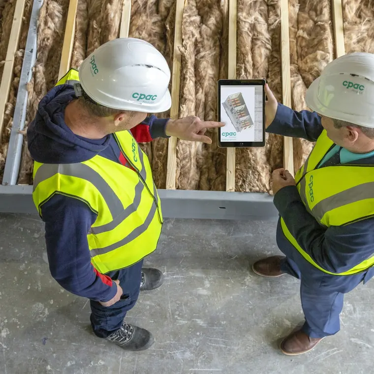Dos trabajadores con casco revisando planos en una tableta en obra